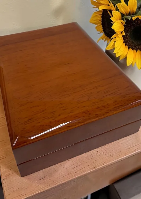 Wooden eMemorybox with a polished lid, sunflowers behind it